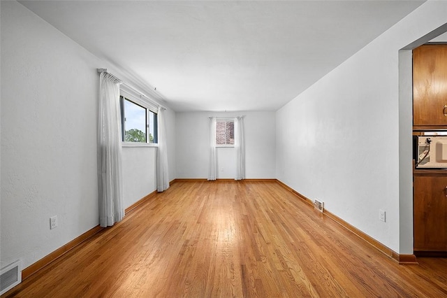 unfurnished room with light wood-type flooring and baseboards