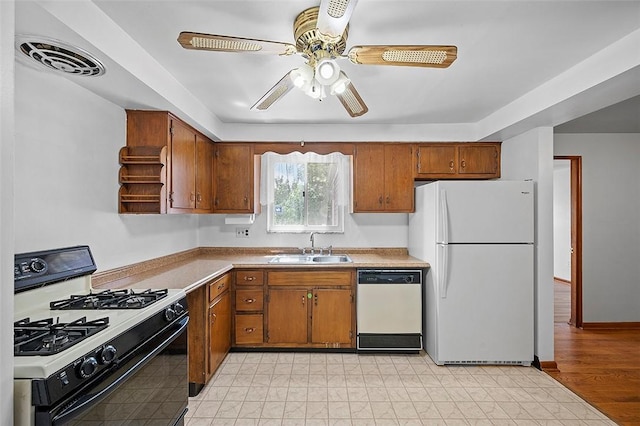 kitchen featuring white appliances, a sink, brown cabinetry, and a ceiling fan