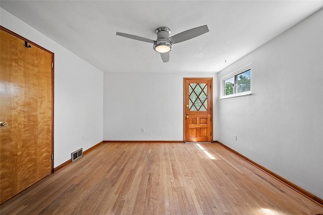 empty room featuring light wood-style floors, a ceiling fan, and baseboards