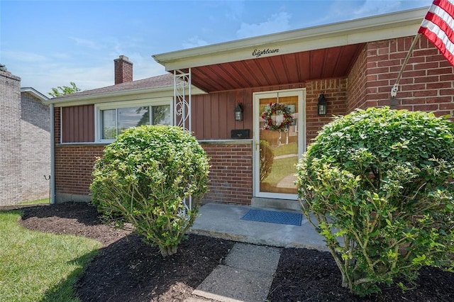 property entrance with brick siding, board and batten siding, and a chimney