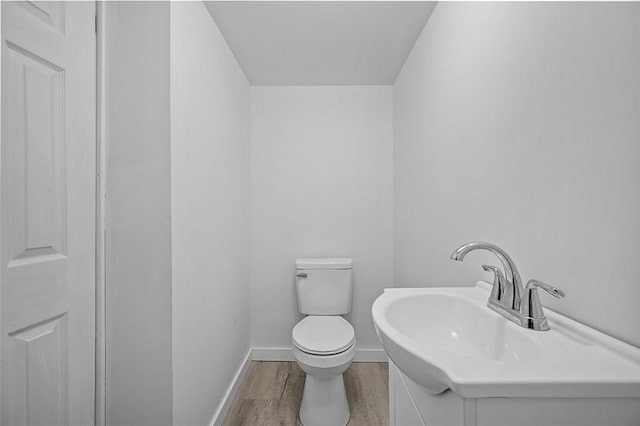 bathroom with wood finished floors, baseboards, toilet, and vanity
