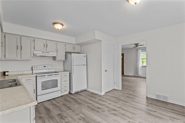 kitchen with white appliances, under cabinet range hood, light countertops, light wood finished floors, and a sink