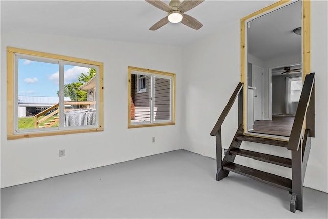 staircase featuring ceiling fan and concrete floors