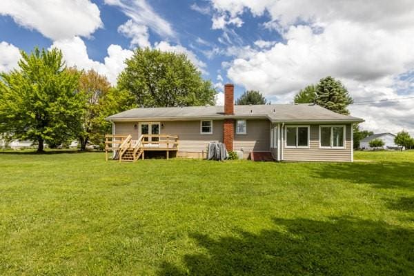back of house featuring a deck, a chimney, and a yard
