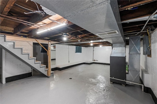 unfinished below grade area featuring heating unit, stairs, and electric panel