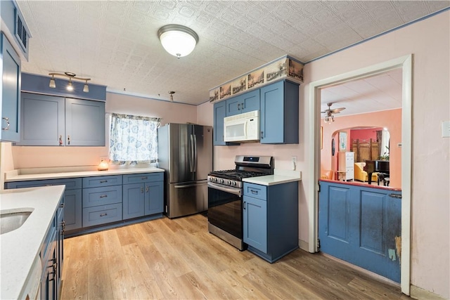 816 E 11th Ave, Munhall, PA 15120 - kitchen featuring stainless steel appliances, light countertops, light wood finished floors, and blue cabinets