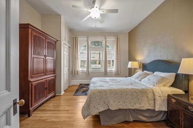 bedroom with light wood-type flooring, a ceiling fan, and baseboards