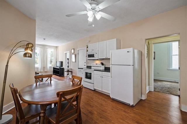 kitchen with white appliances, healthy amount of natural light, white cabinets, and dark wood-style floors