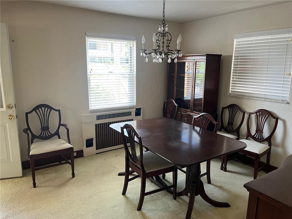 233 Clairmont Ave, West View, PA 15229 - dining room featuring radiator heating unit, light colored carpet, and a chandelier