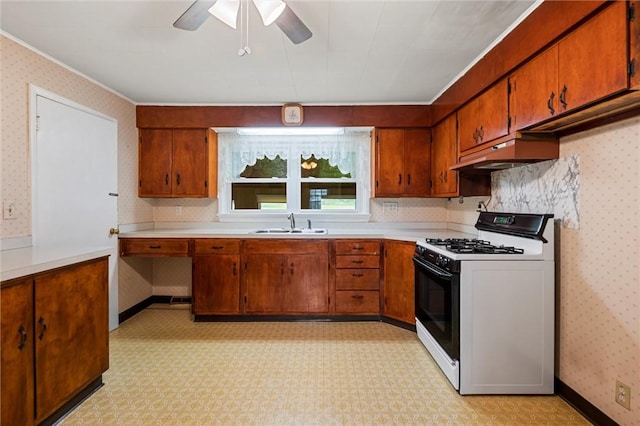 3601 Sharon Rd, West Middlesex Boro, PA 16159 - kitchen featuring range with gas stovetop, brown cabinetry, under cabinet range hood, light flooring, and wallpapered walls