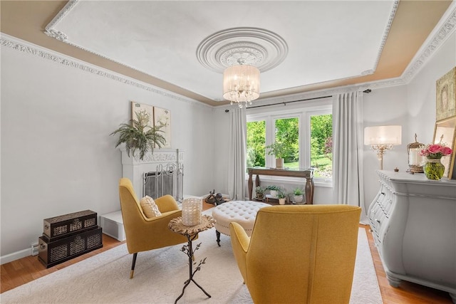 living room featuring a chandelier, wood finished floors, a tray ceiling, ornamental molding, and baseboards