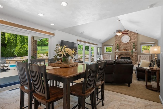 dining room with ceiling fan, lofted ceiling, a fireplace, stone tile flooring, and recessed lighting