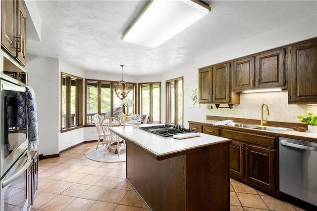 114 Moore Dr, Peters Twp, PA 15317 - kitchen featuring appliances with stainless steel finishes, a sink, light tile patterned floors, a kitchen island, and decorative backsplash