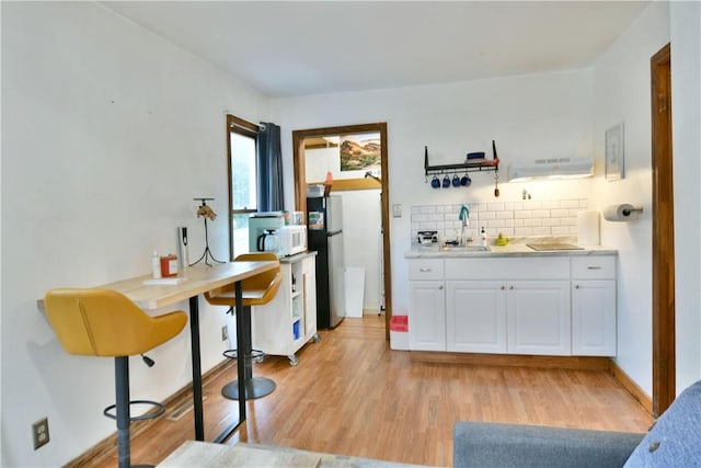 375 Main St, Volant Boro, PA 16156 - kitchen with freestanding refrigerator, white microwave, light wood-style flooring, tasteful backsplash, and a sink