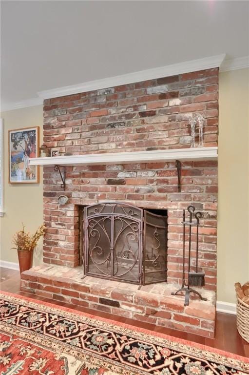 detailed view of crown molding, baseboards, wood finished floors, a brick fireplace, and a wood stove