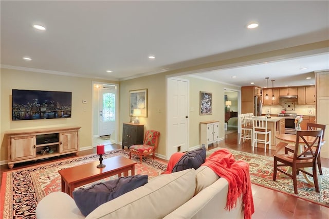 living area featuring ornamental molding, recessed lighting, wood finished floors, and baseboards