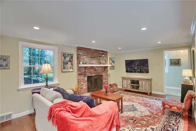 living area featuring baseboards, a brick fireplace, wood finished floors, and recessed lighting