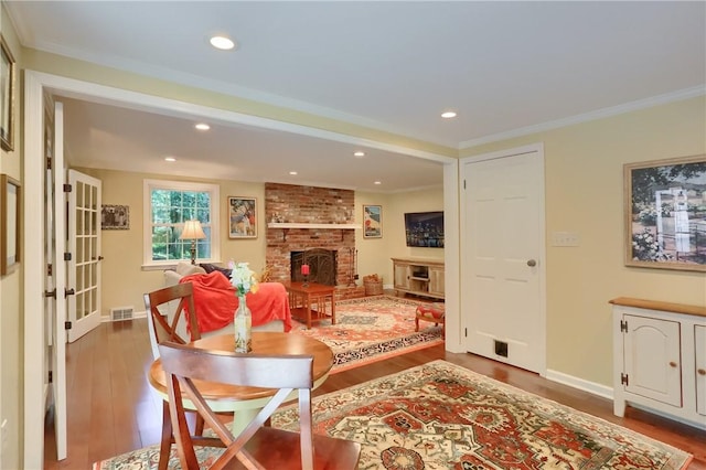 living room featuring wood finished floors, a fireplace, recessed lighting, crown molding, and baseboards