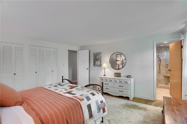 bedroom with light wood-style flooring, multiple closets, baseboards, and ensuite bath