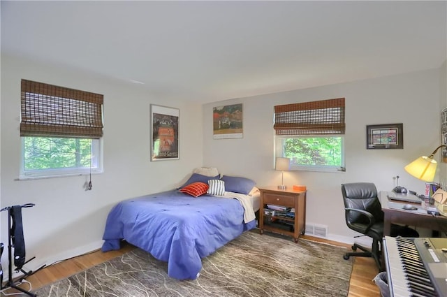 bedroom with multiple windows, wood finished floors, and an office area