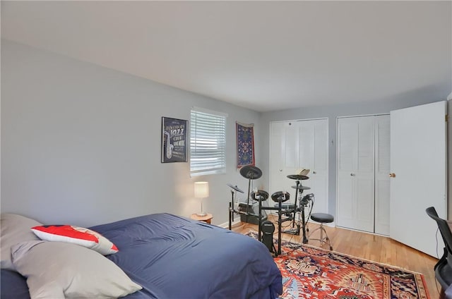 bedroom with multiple closets and light wood-style floors