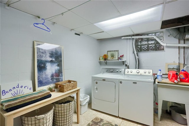 laundry room with independent washer and dryer and concrete block wall