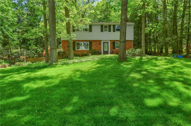 view of front facade with a chimney, a front lawn, and brick siding