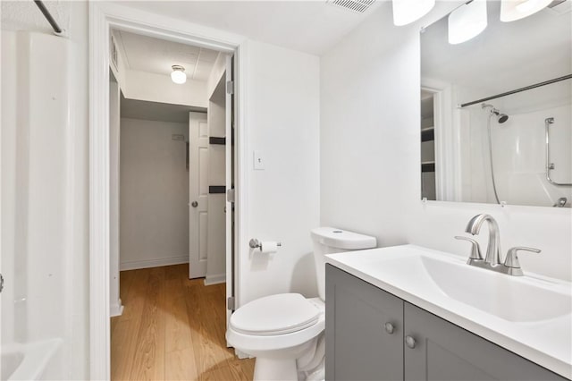 bathroom featuring a shower with shower curtain, wood finished floors, toilet, and vanity