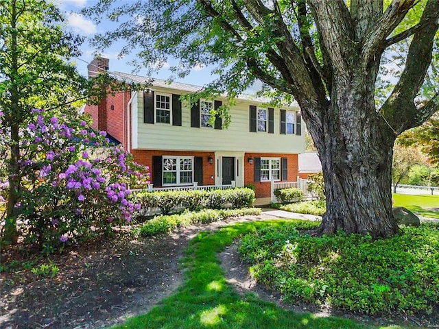 colonial home featuring brick siding and a chimney