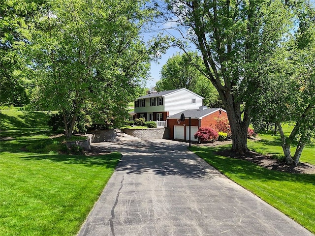 colonial inspired home featuring driveway, a front lawn, and an attached garage
