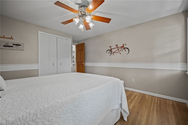 bedroom featuring wood finished floors, baseboards, a closet, and a ceiling fan
