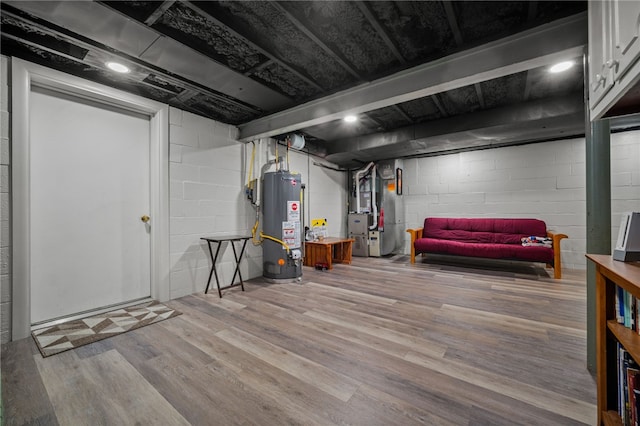 finished below grade area featuring gas water heater, heating unit, and wood finished floors