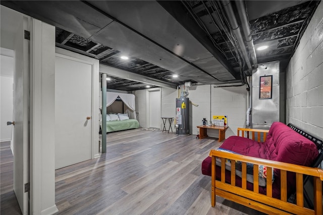 finished basement featuring water heater, wood finished floors, and concrete block wall