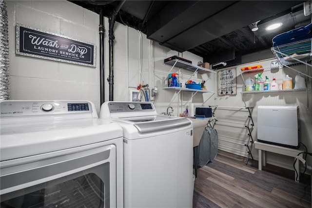 clothes washing area with separate washer and dryer, wood finished floors, and concrete block wall