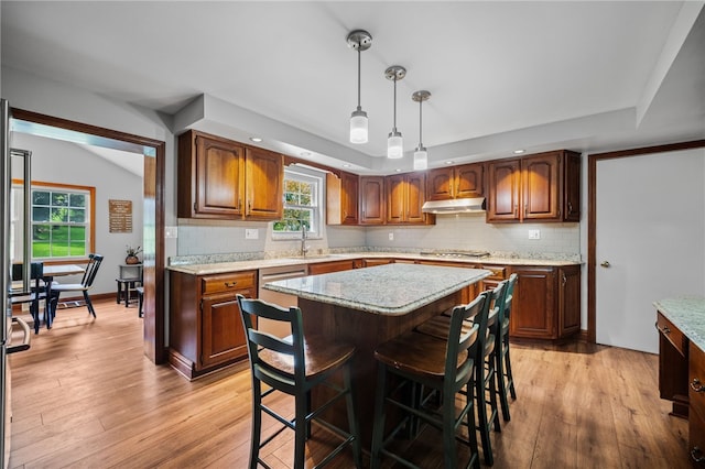 kitchen featuring under cabinet range hood, stainless steel gas stovetop, light wood-style floors, tasteful backsplash, and recessed lighting