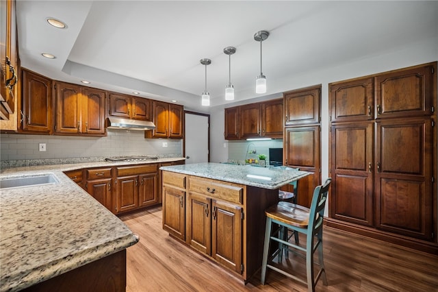 kitchen featuring stainless steel gas stovetop, recessed lighting, a kitchen island, light wood-style floors, and decorative backsplash