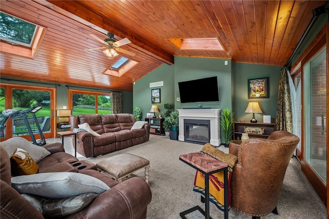 living room featuring a skylight, carpet floors, wood ceiling, a glass covered fireplace, and a ceiling fan