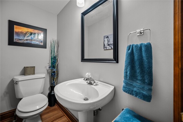 half bath featuring toilet, a sink, and wood finished floors