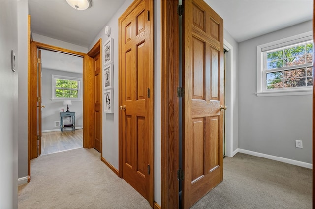 hallway with light colored carpet and baseboards