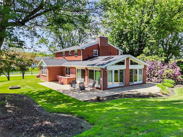 back of property featuring a chimney, a patio area, brick siding, and a fire pit
