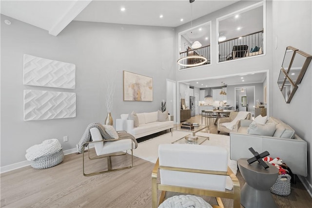 living room featuring light wood-style flooring, a high ceiling, recessed lighting, and baseboards