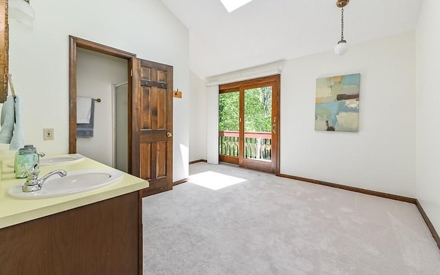full bath with baseboards, a skylight, lofted ceiling, and double vanity