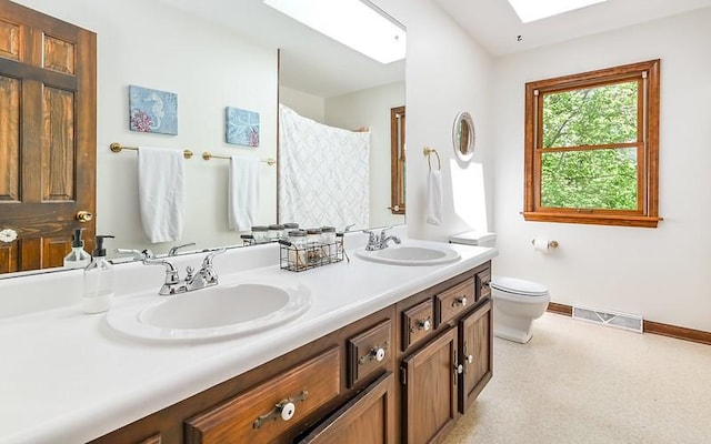 full bath featuring baseboards, toilet, double vanity, a skylight, and a shower with curtain