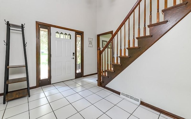 foyer featuring baseboards, stairs, a high ceiling, and light tile patterned floors