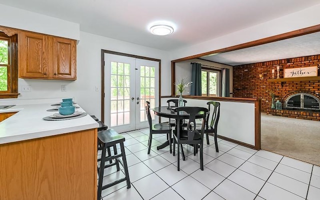 dining area with french doors, light tile patterned flooring, light carpet, and a fireplace