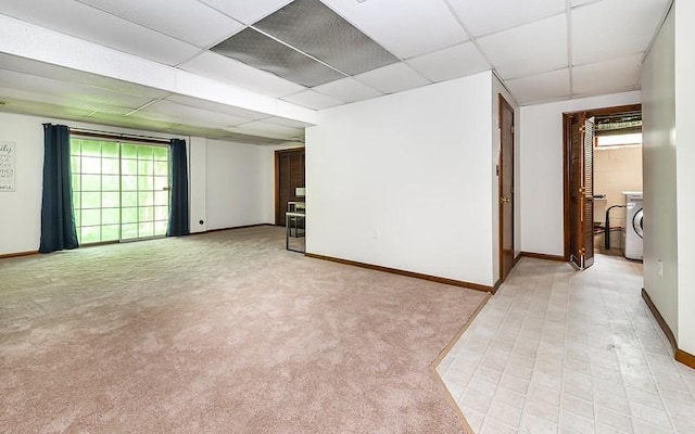 unfurnished room with washer / clothes dryer, a drop ceiling, healthy amount of natural light, and baseboards