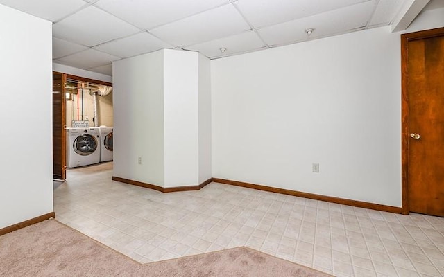 unfurnished room featuring a paneled ceiling, washer and dryer, baseboards, and a pendent fire sprinkler