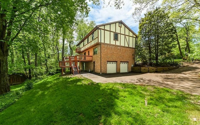rear view of house with driveway, a wooden deck, stairway, an attached garage, and a lawn