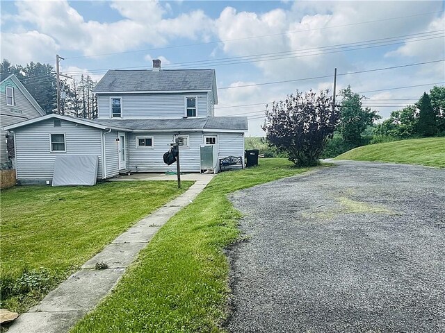 128 Cessna Hill Rd, Jenner Twp, PA 15531 - back of house featuring driveway, a lawn, a patio area, and a chimney