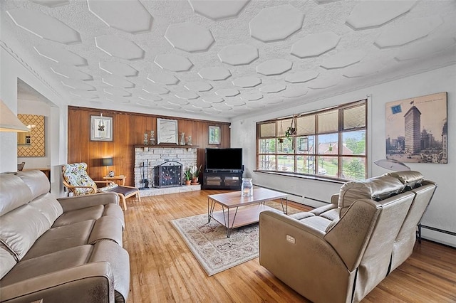 426 Oliver Dr, White Oak, PA 15131 - living room featuring a stone fireplace, wood finished floors, wooden walls, and a baseboard radiator